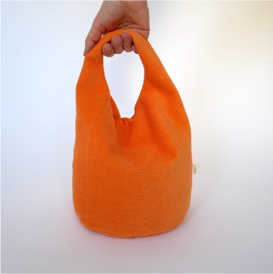 Türstopper Carrot Cordulino mit Baumwoll-Cordbezug von stop!t Produktfoto mit menschlicher Hand am Tragegriff.