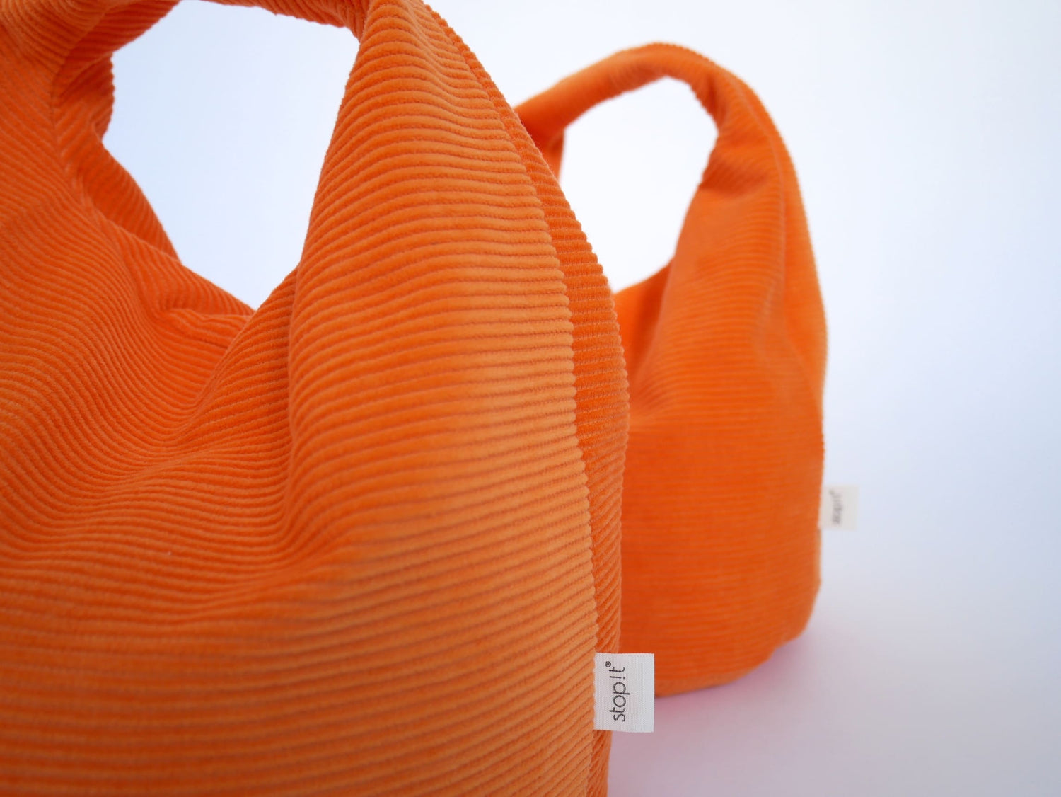 2 Türstopper Carrot Cordulino mit Baumwoll-Cordbezug von stop!t dekorativ in Nahaufnahme schräg hintereinander.