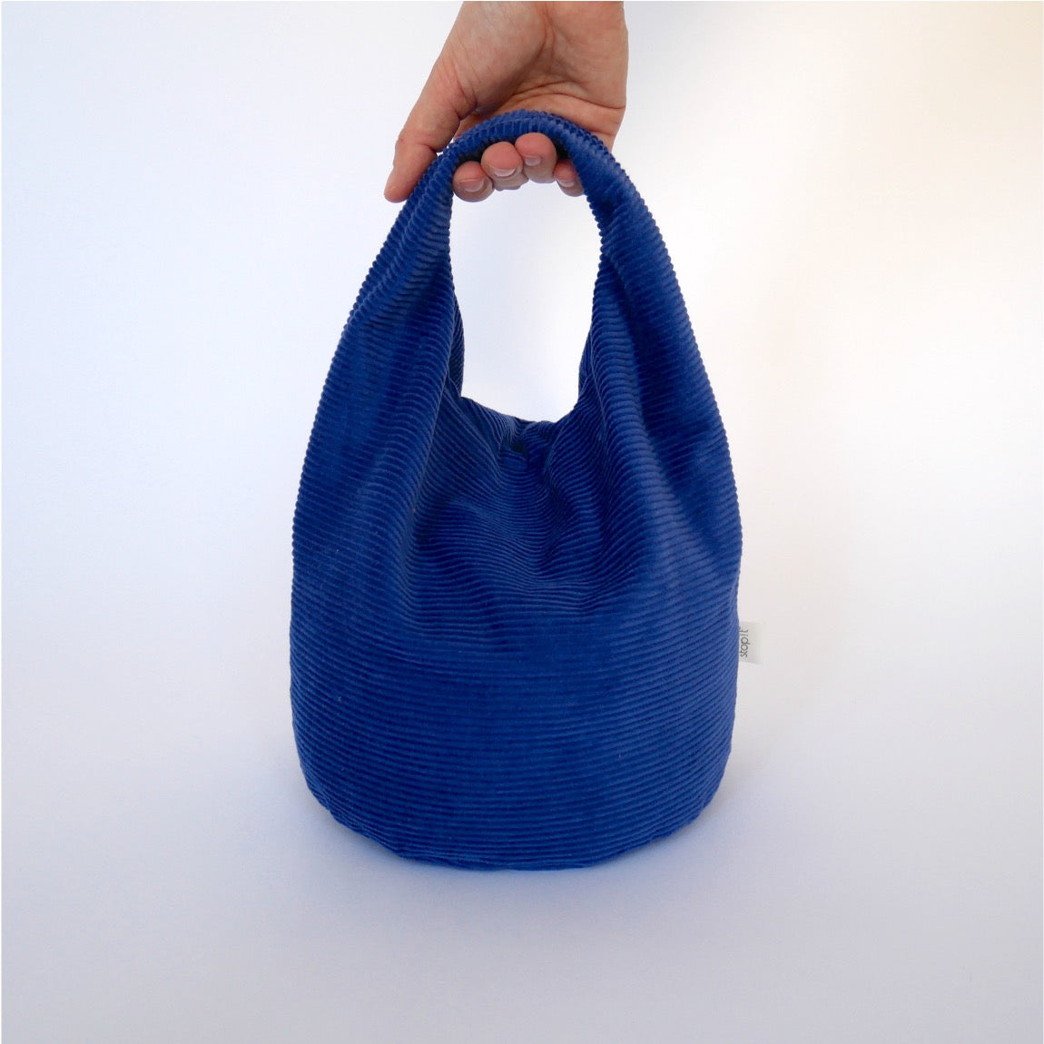 Türstopper Cobalt Cordulino mit Baumwoll-Cordbezug von stop!t Produktfoto mit menschlicher Hand am Tragegriff.
