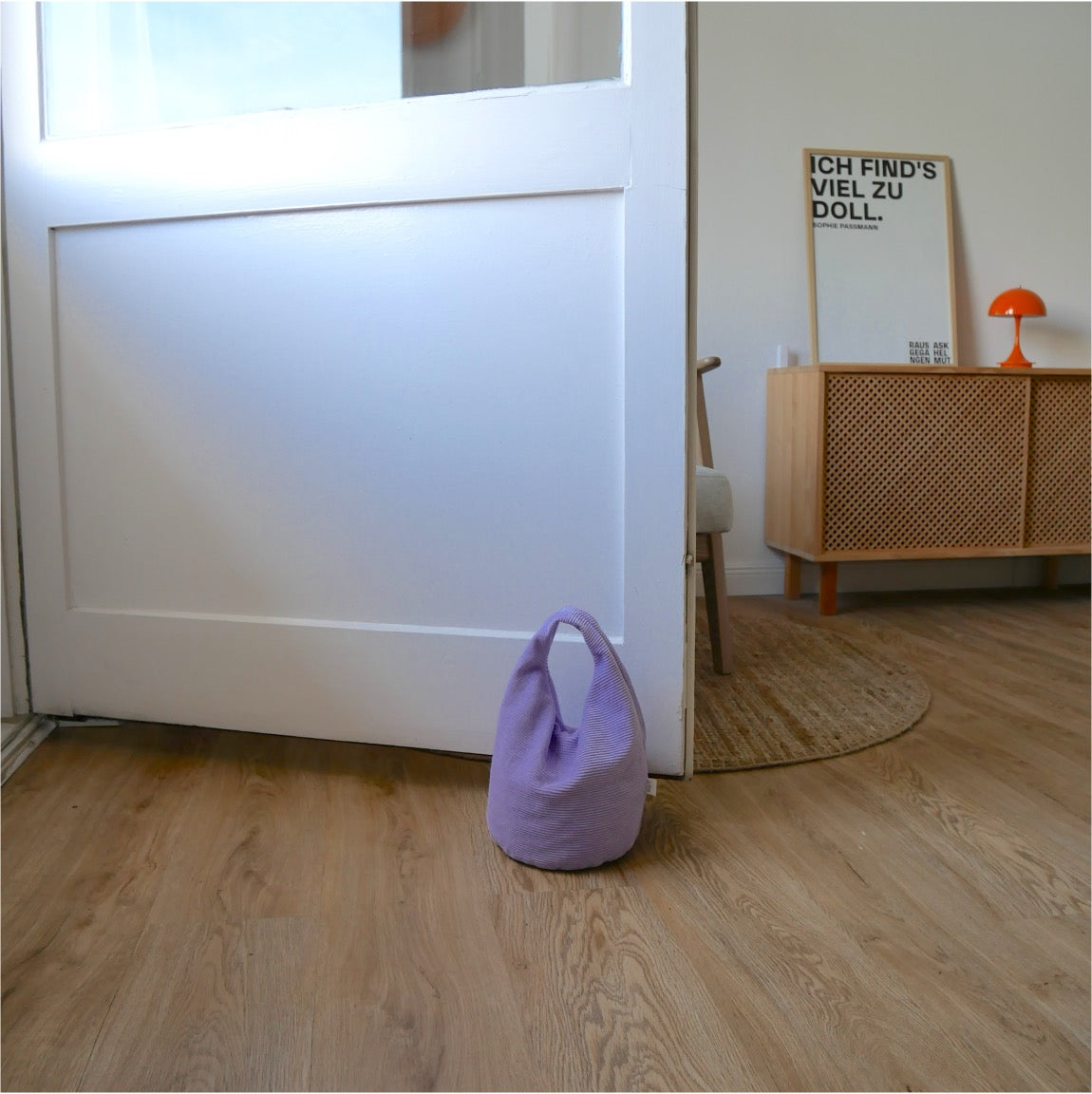Türstopper Cordulino Lilac Tree mit Baumwoll-Cordbezug von stop!t Produktfoto vor einer Balkontür demonstrierend die Tür vor Zugluft stoppend.