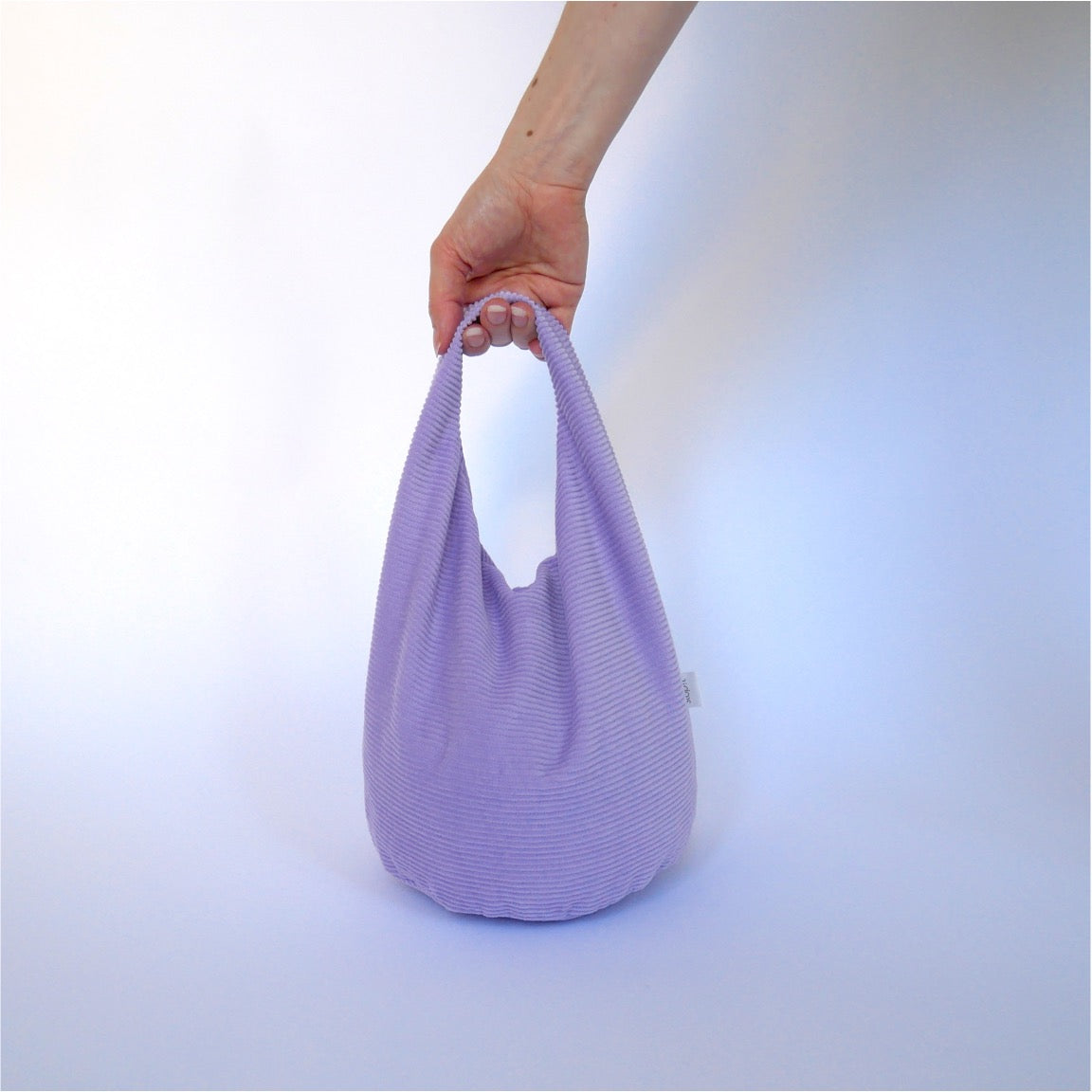 Türstopper Cordulino Lilac Tree mit Baumwoll-Cordbezug von stop!t Produktfoto mit menschlicher Hand am Tragegriff.