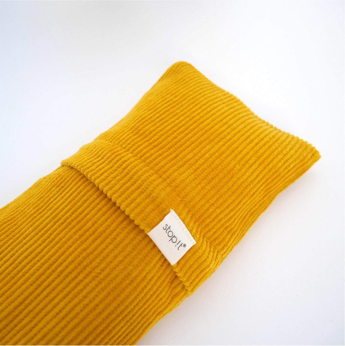stopit Zugluftstopper Mustard Cordula Produktfoto. Produkt liegt schräg von links unten nach rechts oben und zeigt die dekorative Lasche, die Zugang zum Inlett schafft.