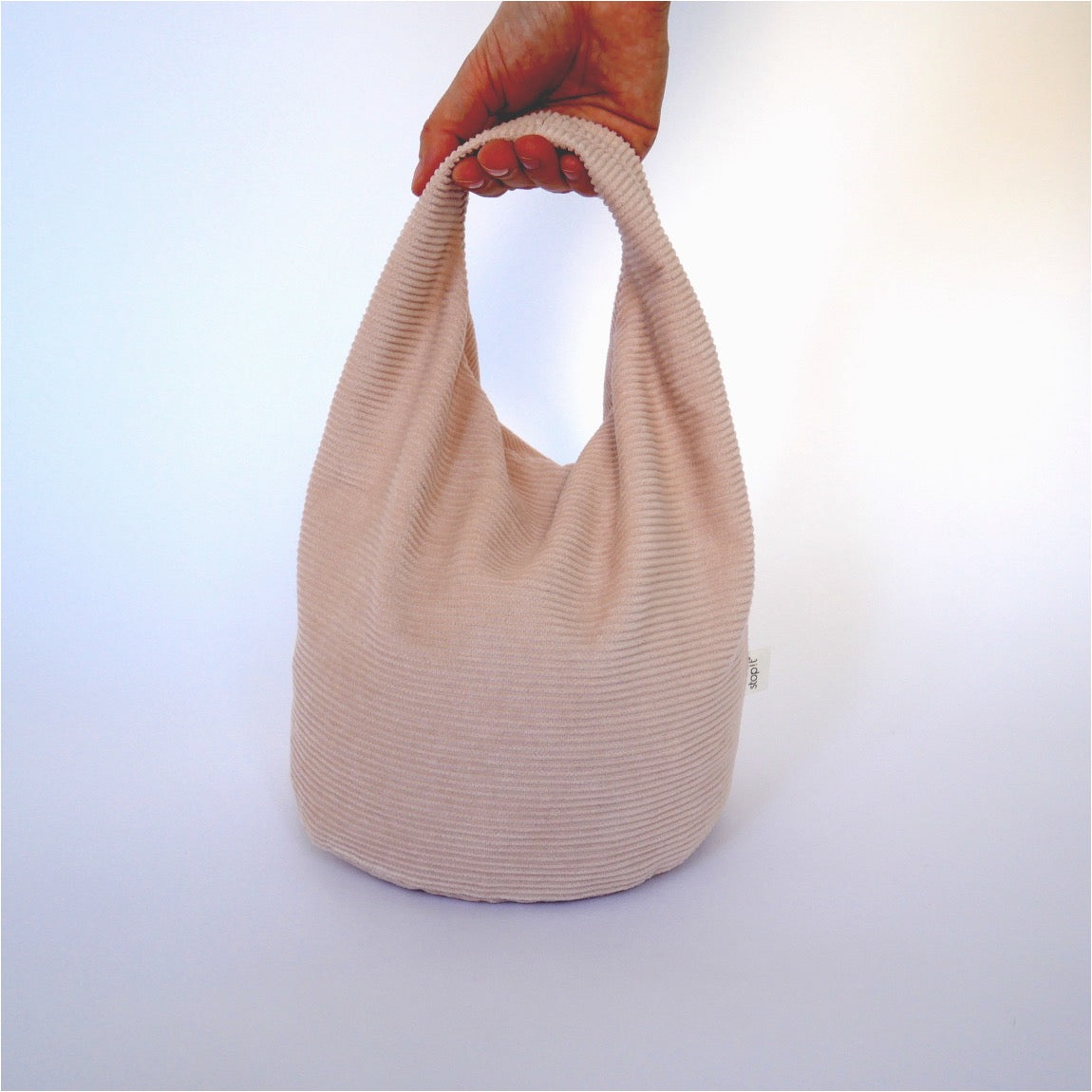 Türstopper Cotton Candy Cordulino mit Baumwoll-Cordbezug von stop!t Produktfoto mit menschlicher Hand am Tragegriff.